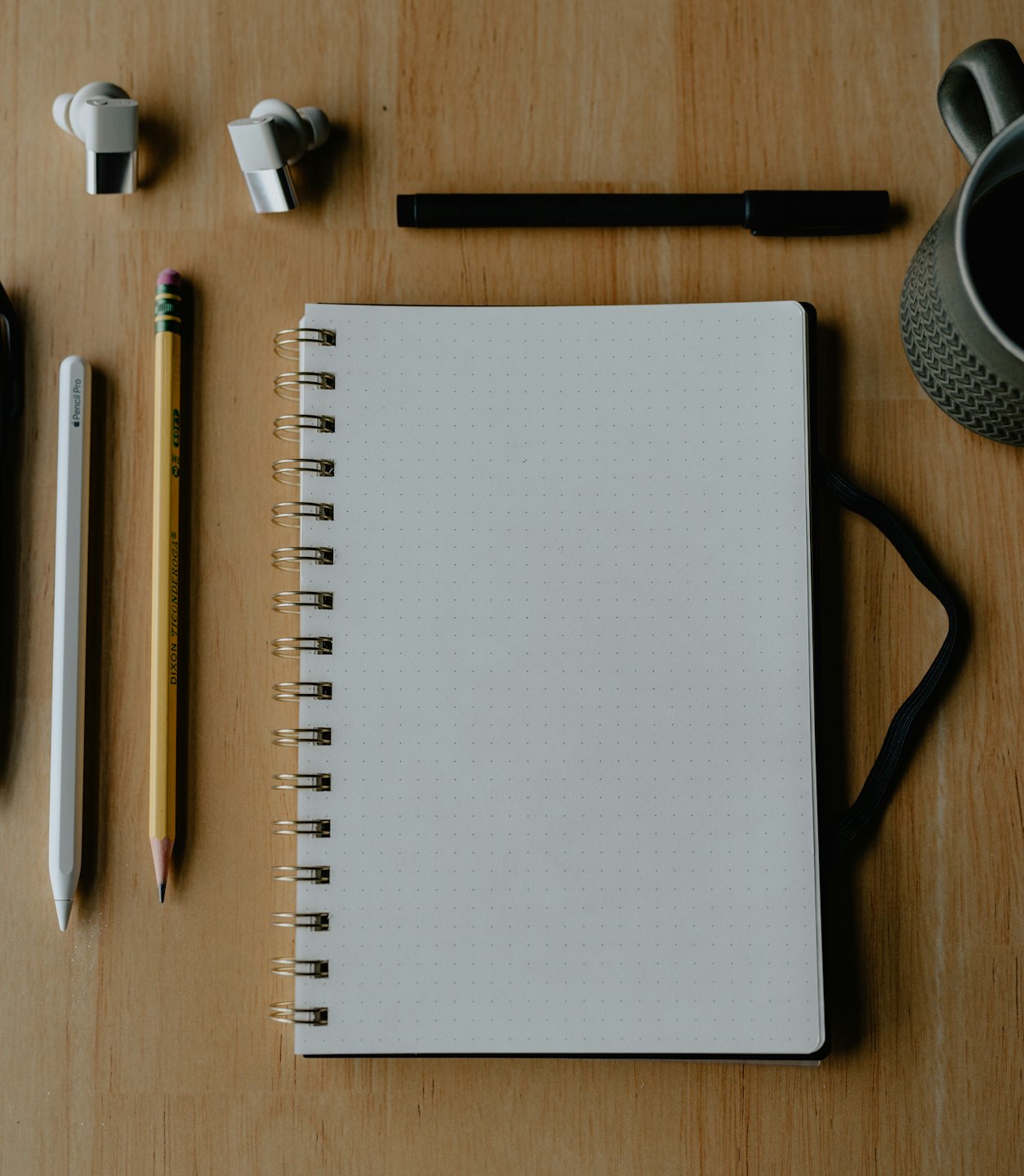 Office supplies and coffee cup on a wooden desk.